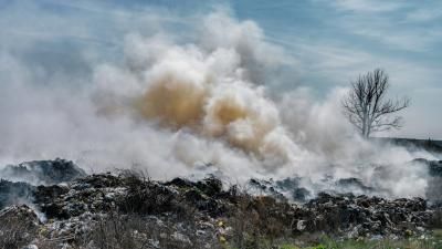 A pile of waste burning, plumes of smoke can be seen.